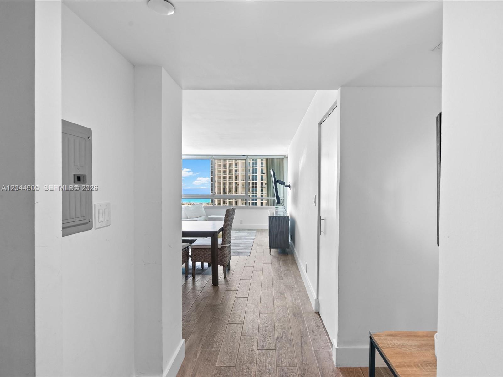 A hallway leads to a dining area with wood-look flooring and a view of buildings — 400 S Pointe Dr # 1102, Miami Beach FL 33139, MIAMI BEACH, FL