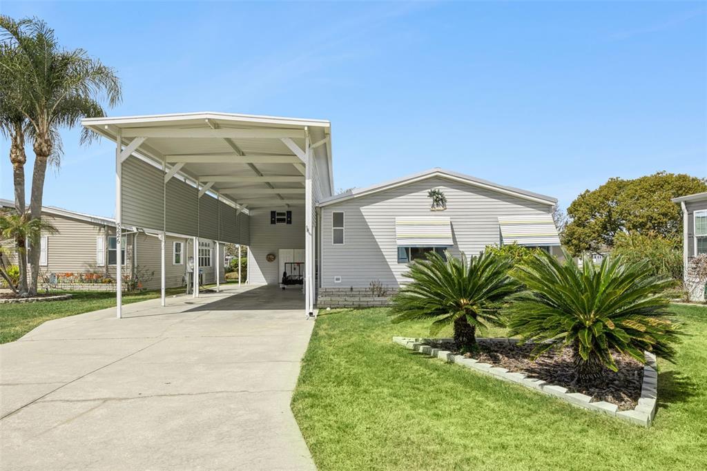 A single-story house with light gray siding, a large carport, and two palm trees — 5226 ISLAND VIEW CIRCLE N, POLK CITY, FL