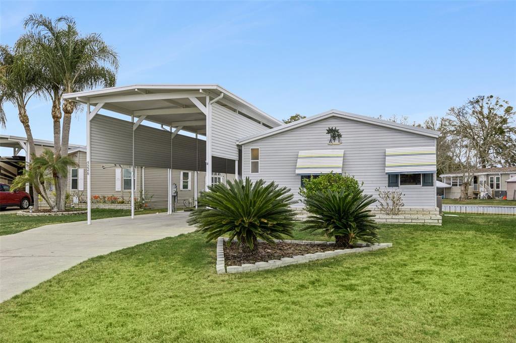 A light gray manufactured home features a large attached carport and two prominent sago palms — 5226 ISLAND VIEW CIRCLE N, POLK CITY, FL