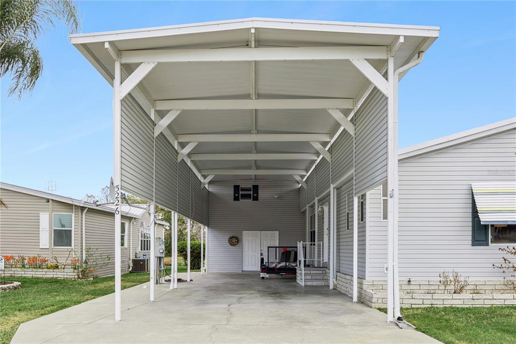 A concrete driveway leads to a covered carport attached to a light gray mobile home — 5226 ISLAND VIEW CIRCLE N, POLK CITY, FL