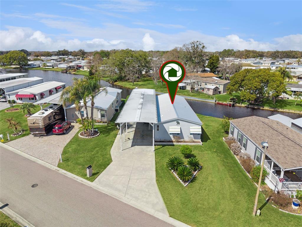 An aerial view shows a light-colored mobile home with a carport beside a canal — 5226 ISLAND VIEW CIRCLE N, POLK CITY, FL
