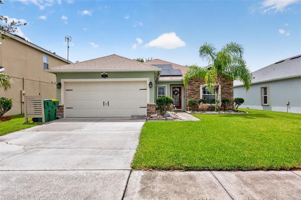 A single-story house with a two-car garage, stone facade, and a palm tree in front — 1465 LITCHFIELD DRIVE, WEST MELBOURNE, FL