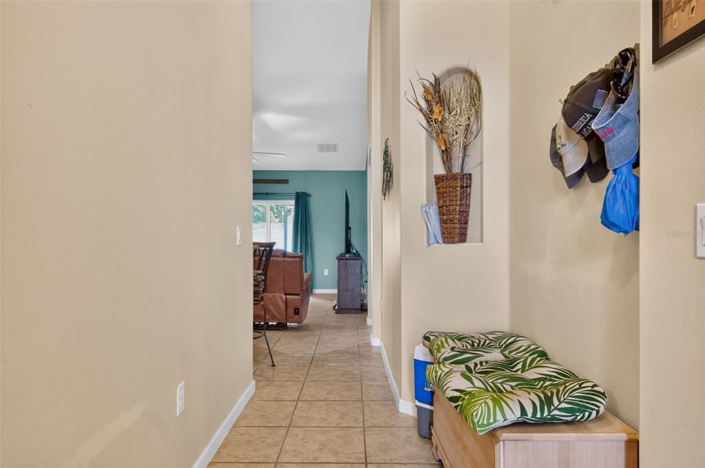A hallway with tile flooring leads to a living area featuring a built-in wall niche — 1465 LITCHFIELD DRIVE, WEST MELBOURNE, FL