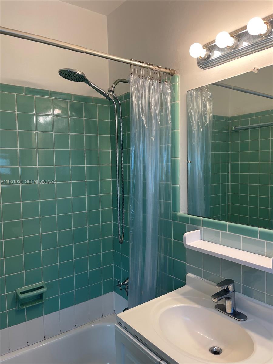 A bathroom features teal square wall tiles, a shower-tub combination, and a vanity with a mirror — 10178 Collins Ave # 202, Bal Harbour FL 33154, BAL HARBOUR, FL