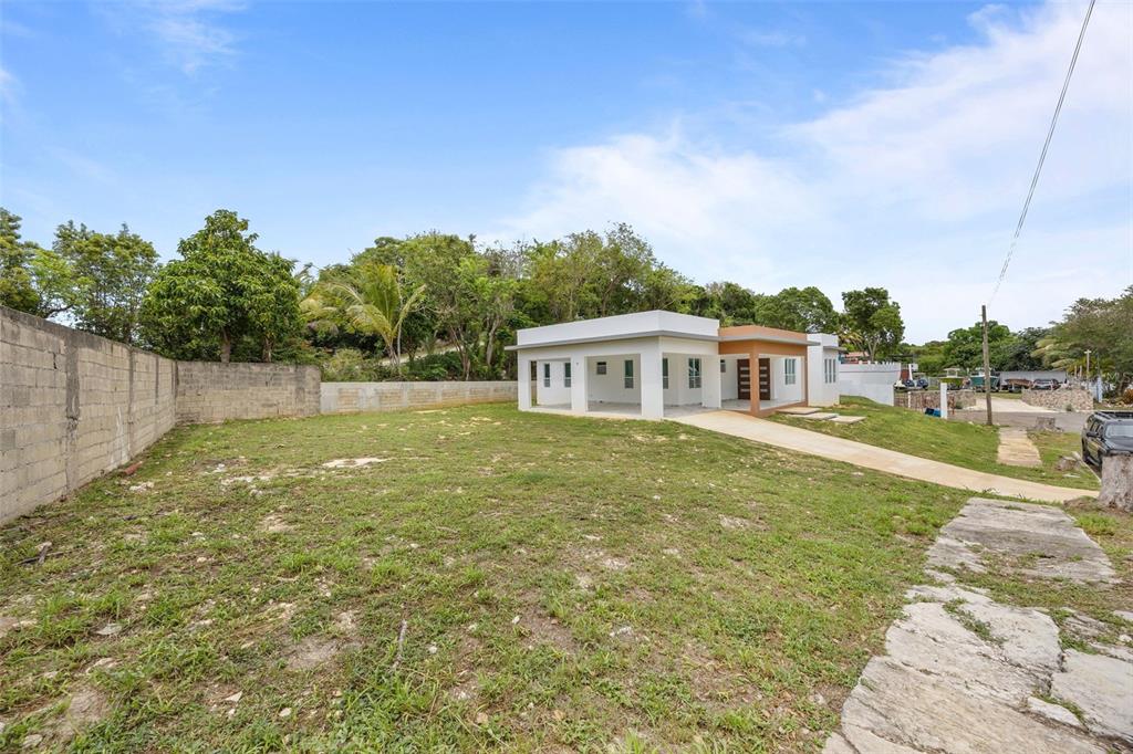 A modern, single-story house with a large, grassy yard and a concrete block wall — solar 2 villa alemeria MARCEL, AGUADILLA, PR