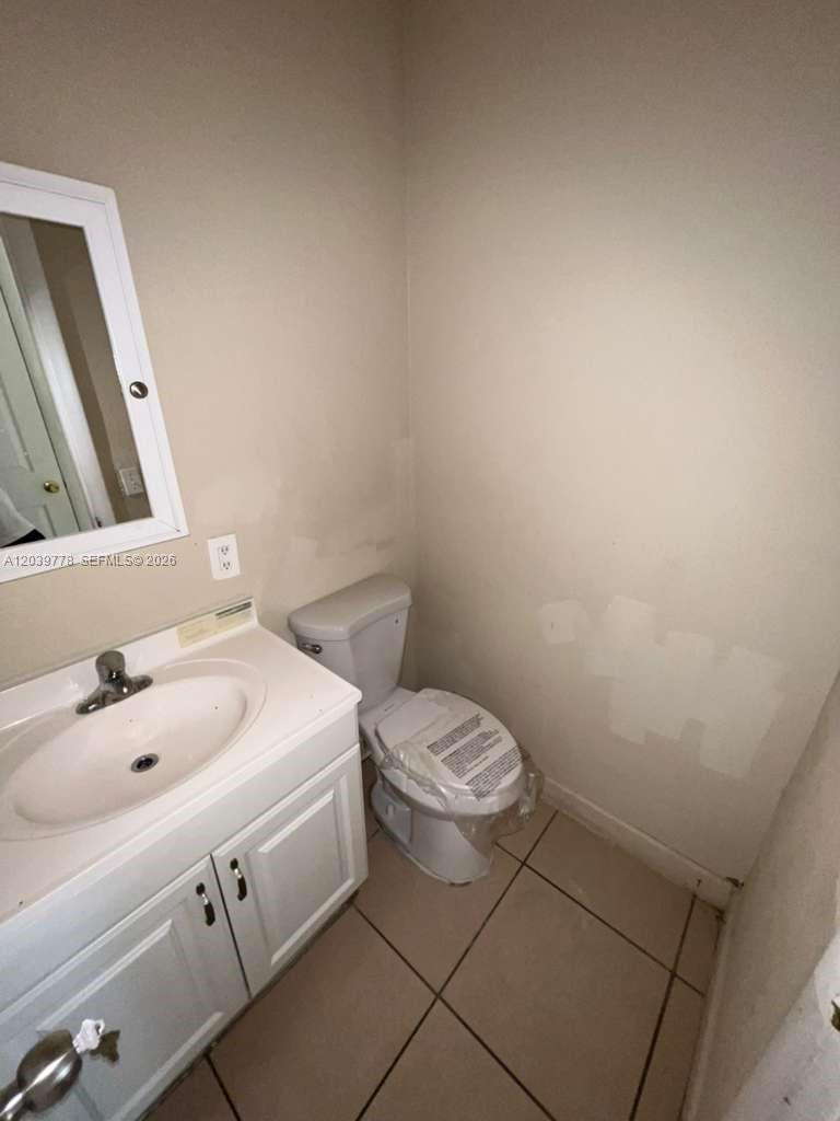 A small bathroom features a white vanity, a toilet with a plastic-wrapped seat, and tile flooring — 4625 NW 9th Dr # 4625, Plantation FL 33317, PLANTATION, FL
