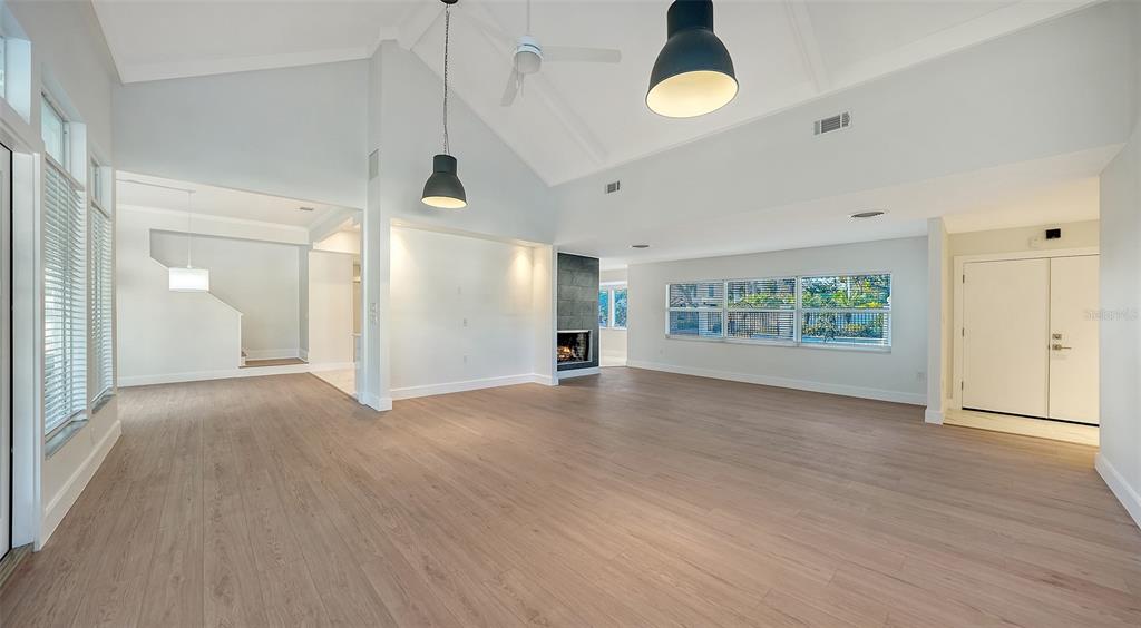 A spacious living room features light wood flooring, a vaulted ceiling, and a stone fireplace — 940 ALAMEDA WAY, SARASOTA, FL