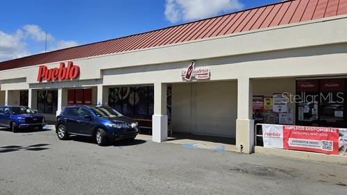 A blue SUV is parked in front of a Pueblo supermarket storefront with a red roof — PR-194 INT EL CONQUISTADOR, FAJARDO, PR