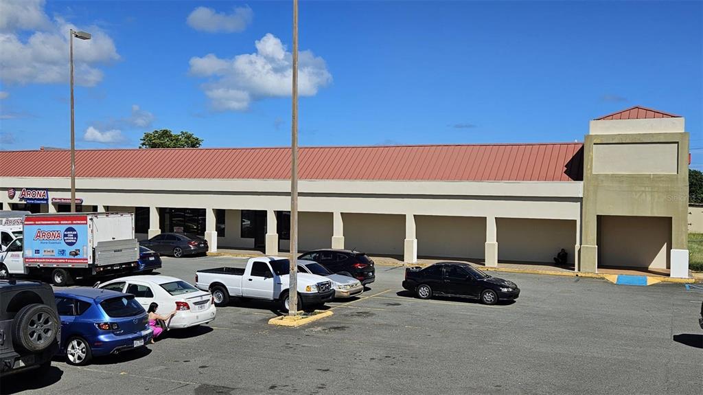 A commercial strip mall building with a red metal roof and a parking lot — PR-194 INT EL CONQUISTADOR, FAJARDO, PR