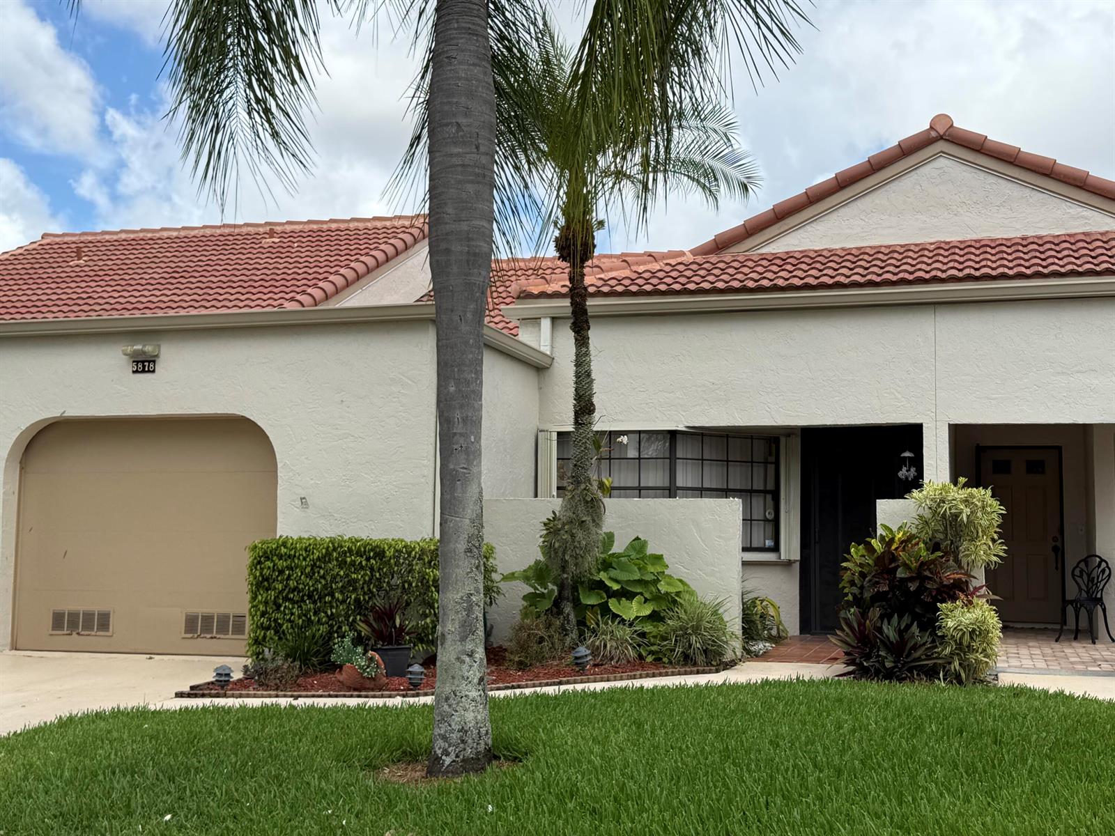 A single-story house with a tan garage, red tile roof, and a front garden — 5878 Parkwalk Circle W, Boynton Beach FL 33472, BOYNTON BEACH, FL