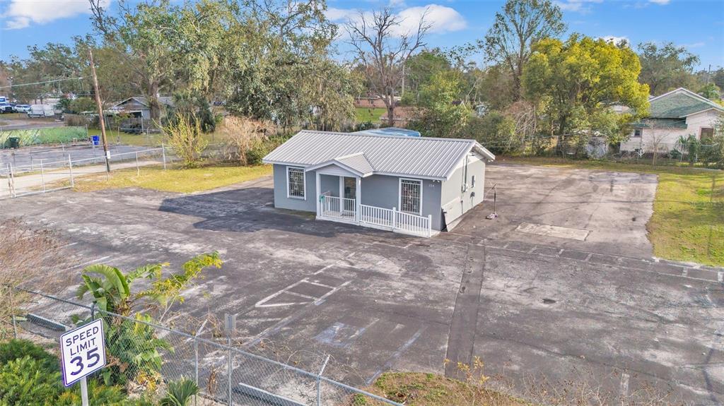 An aerial view shows a small gray building with a metal roof surrounded by asphalt — 214 W MEMORIAL BOULEVARD, LAKELAND, FL
