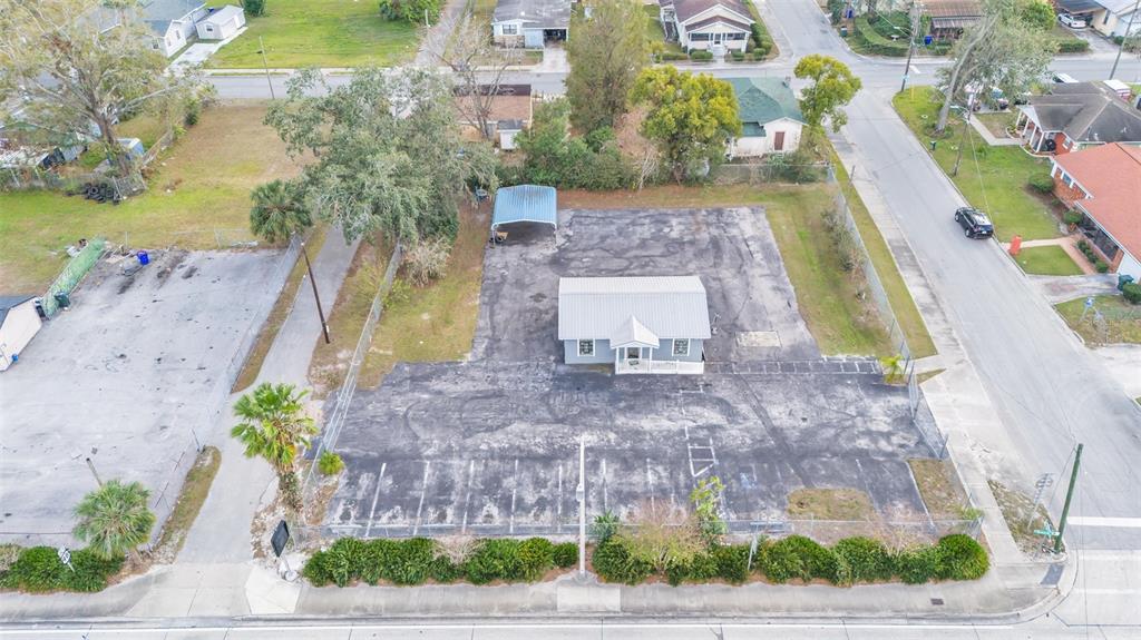 An aerial view shows a small building with a metal roof surrounded by a paved lot — 214 W MEMORIAL BOULEVARD, LAKELAND, FL