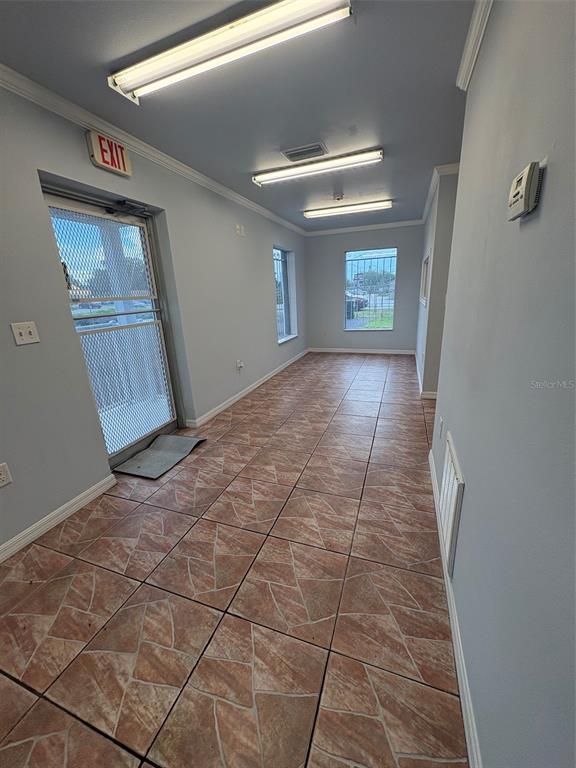An empty commercial room features light blue walls, tiled floors, and three overhead fluorescent lights — 214 W MEMORIAL BOULEVARD, LAKELAND, FL