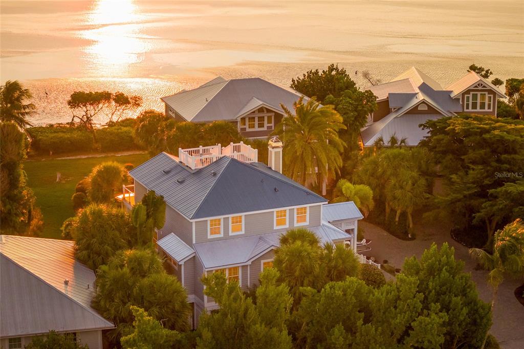 An aerial view shows a multi-story house with a blue metal roof near the water — 367 NIGHT HERON DRIVE, BOCA GRANDE, FL