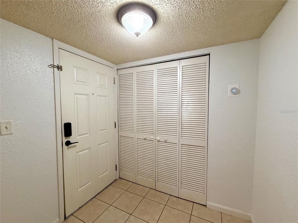 An entryway features a white front door, louvered closet doors, and light-colored floor tiles — 1810 NW 23RD BOULEVARD UNIT 180, GAINESVILLE, FL