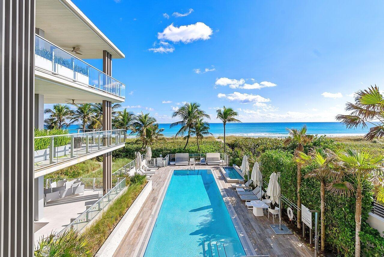 An outdoor swimming pool sits beside a modern building with balconies overlooking the ocean — 1901 S Ocean Boulevard # 10, Delray Beach FL 33483, DELRAY BEACH, FL