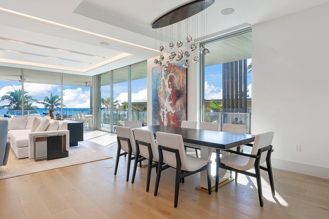 A modern dining room features a dark table, white chairs, and a contemporary glass chandelier — 1901 S Ocean Boulevard # 10, Delray Beach FL 33483, DELRAY BEACH, FL
