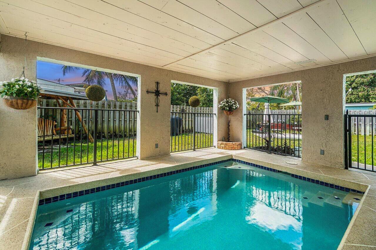 An indoor pool area features a covered patio with a ceiling, tile flooring, and metal railings — 944 Hansen Street, West Palm Beach FL 33405, WEST PALM BEACH, FL