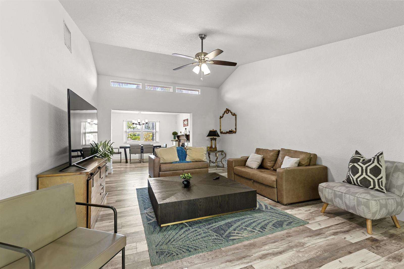 A living room with a large coffee table, leather sofa, and vaulted ceiling — 944 Hansen Street, West Palm Beach FL 33405, WEST PALM BEACH, FL