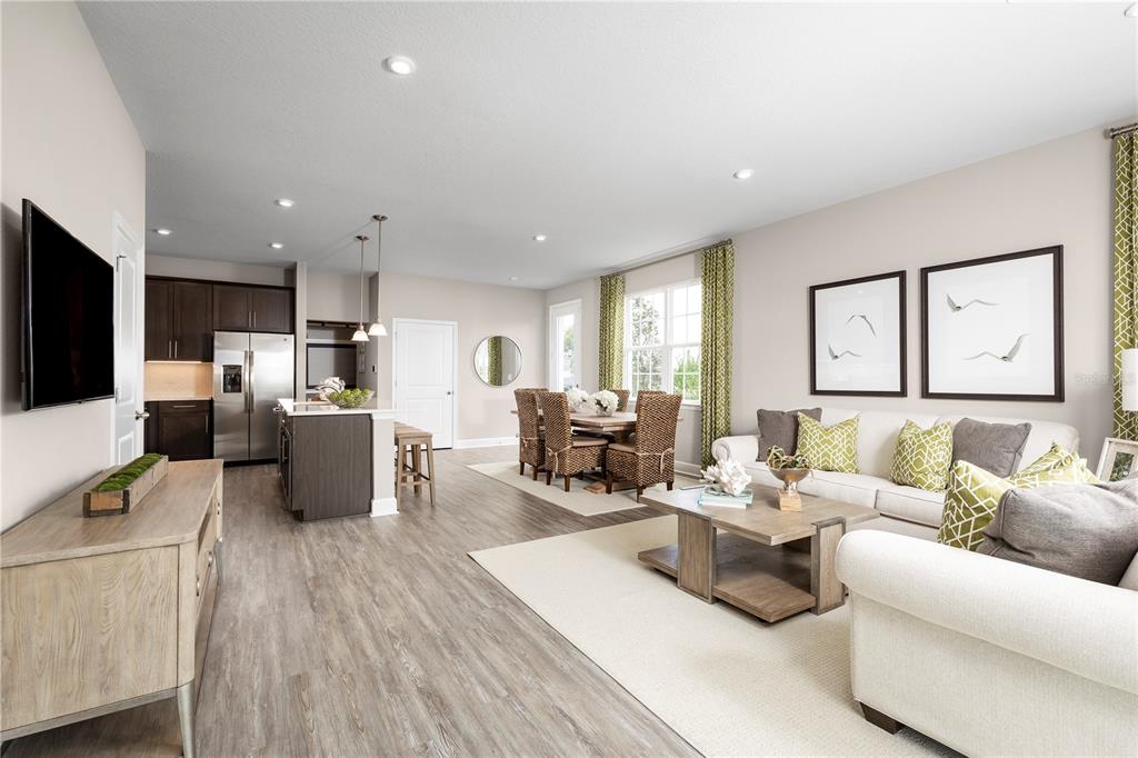 An open-concept living and dining area features light wood flooring, a kitchen island, and furniture — 6644 CEDAR LANDING CIRCLE, LEESBURG, FL