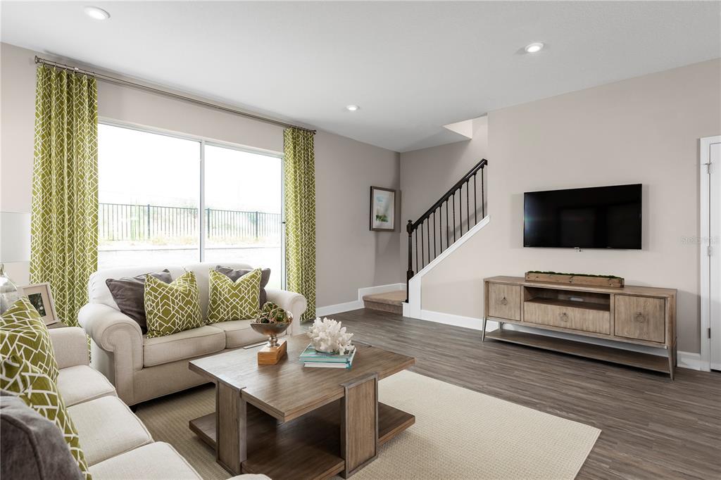 A living room features a beige sofa, wooden coffee table, media console, and a staircase — 6644 CEDAR LANDING CIRCLE, LEESBURG, FL