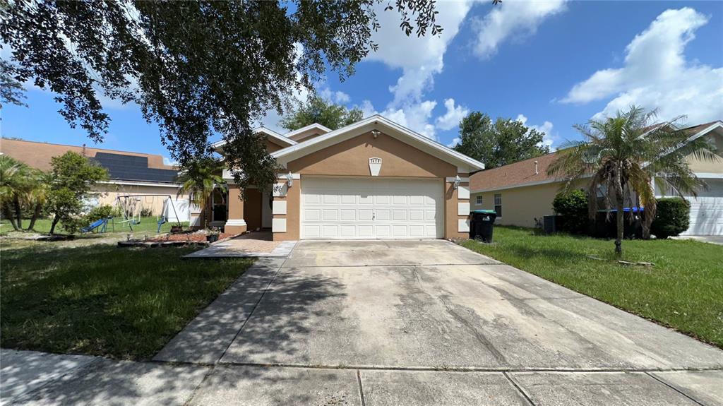 A tan single-story house with a two-car garage and a concrete driveway — 2429 SAPIER COURT, ORLANDO, FL