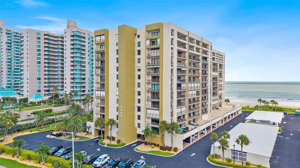 An aerial view of a multi-story apartment building located next to a sandy beach — 1480 GULF BOULEVARD UNIT 409, CLEARWATER BEACH, FL