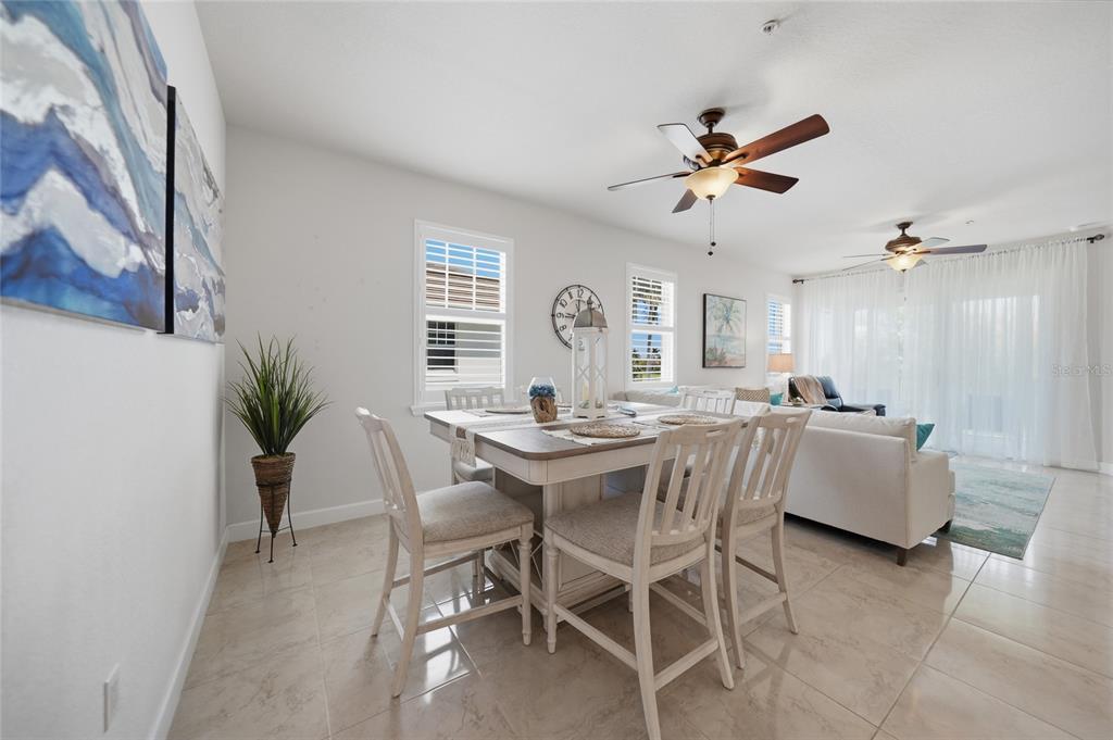 A dining area with a table and chairs sits adjacent to a living room space — 17288 ACAPULCO ROAD UNIT 421, PUNTA GORDA, FL