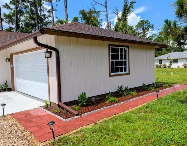 The exterior of a house features a garage, beige siding, and a red brick walkway — 3331 TRAVERSE AVENUE, NORTH PORT, FL