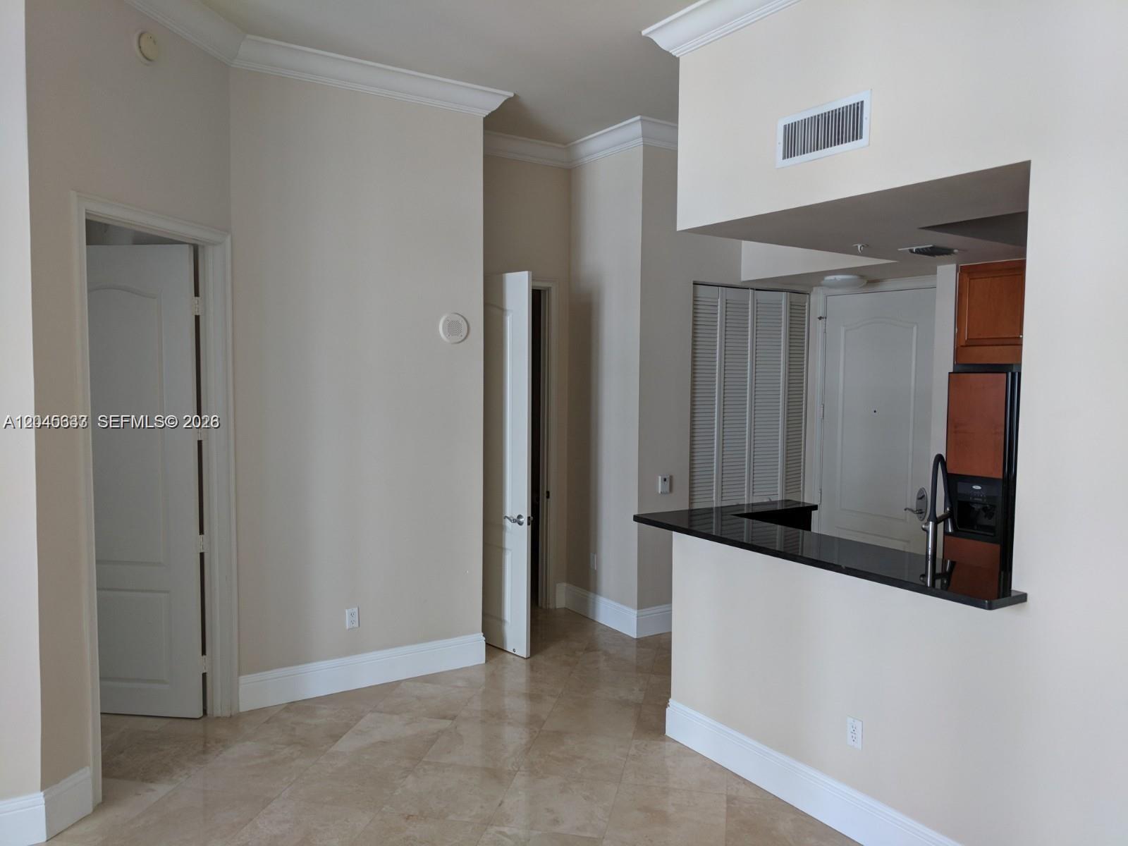 An interior view shows a tiled room with a kitchen pass-through and two open doors — 99 SE Mizner Blvd # 537, Boca Raton FL 33432, BOCA RATON, FL