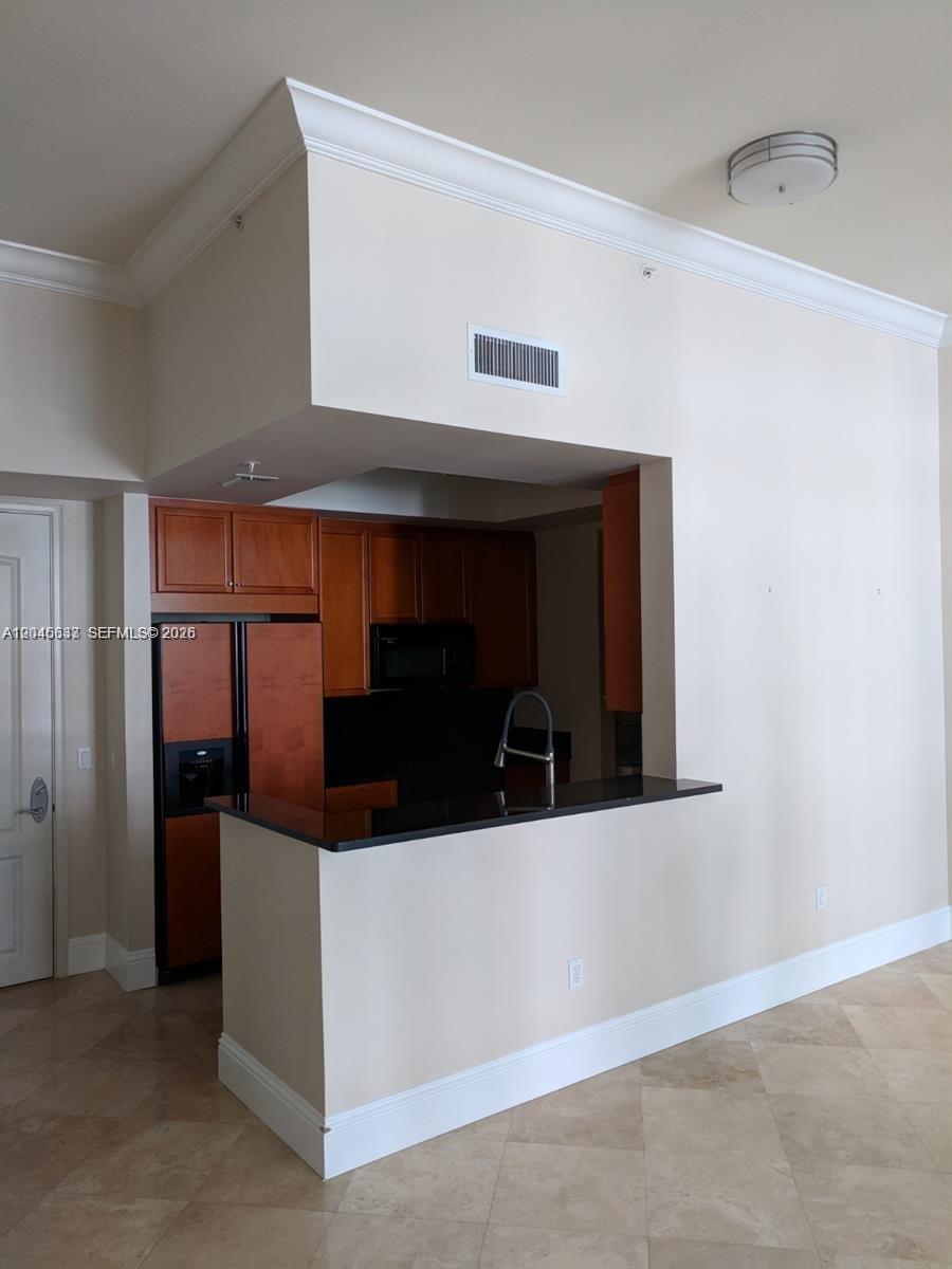 A kitchen with dark wood cabinets and black countertops features a pass-through breakfast bar — 99 SE Mizner Blvd # 537, Boca Raton FL 33432, BOCA RATON, FL