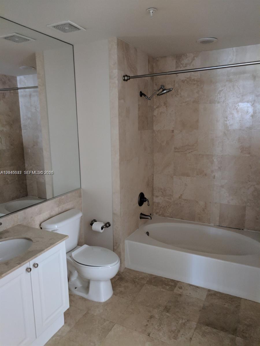 A bathroom features a white vanity, a toilet, and a bathtub with tiled walls — 99 SE Mizner Blvd # 537, Boca Raton FL 33432, BOCA RATON, FL