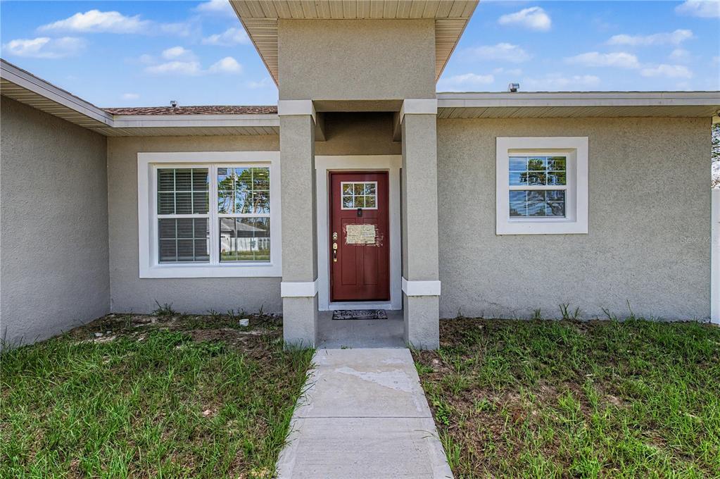 The exterior of a single-story house features a red front door under a covered entryway — 17199 SW 43RD COURT, OCALA, FL