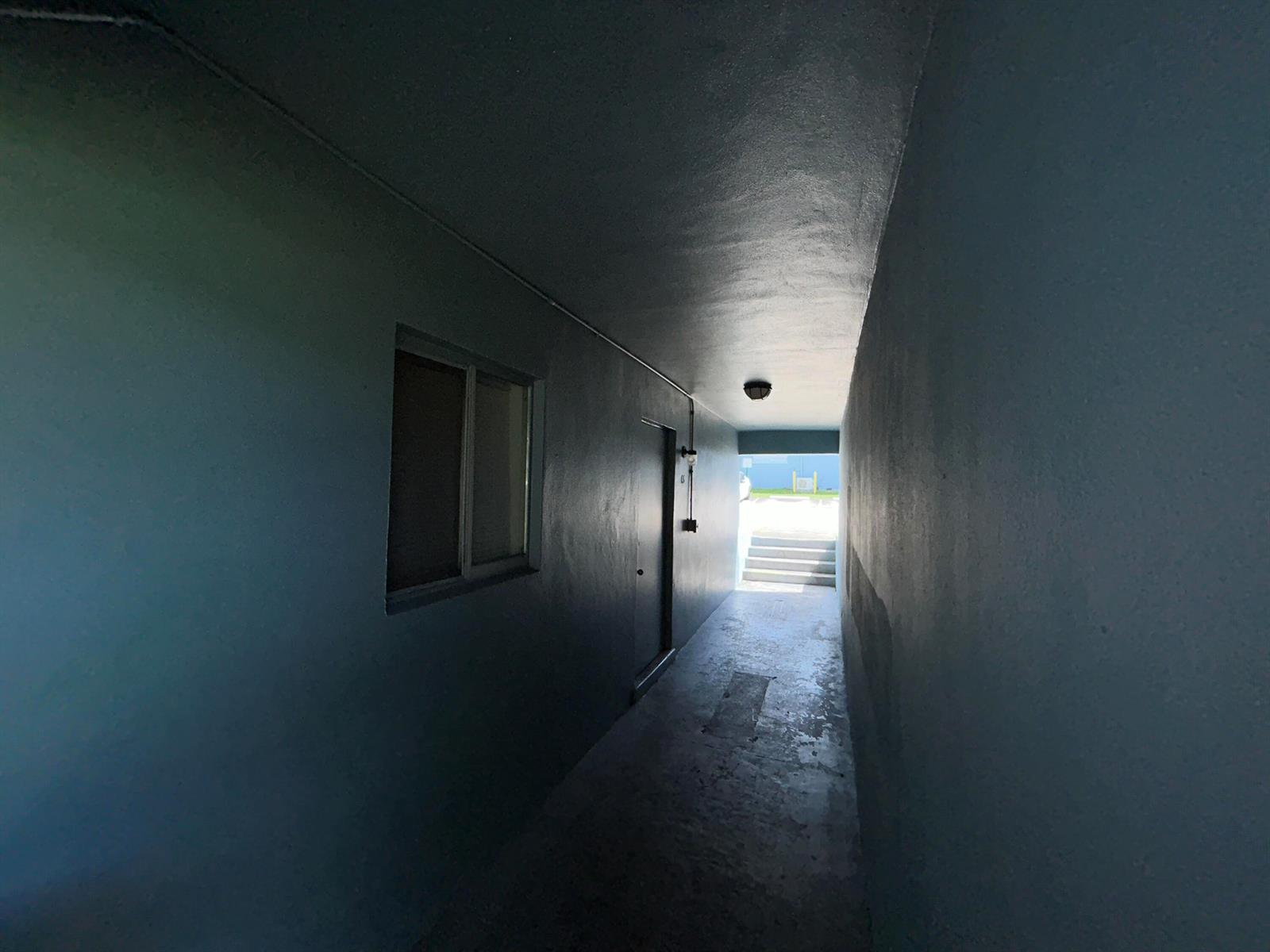 A narrow, blue-walled outdoor corridor leads toward a set of concrete stairs — 1829 N A Street # 65, FL 33460, FL