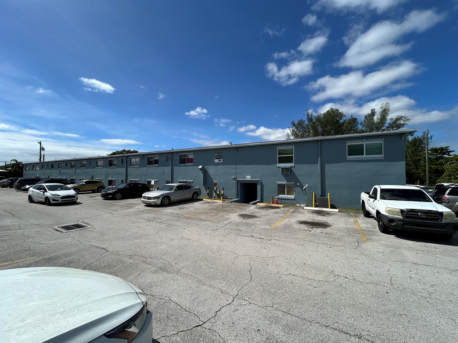 A two-story blue apartment building with a parking lot in front under a blue sky — 1829 N A Street # 65, FL 33460, FL