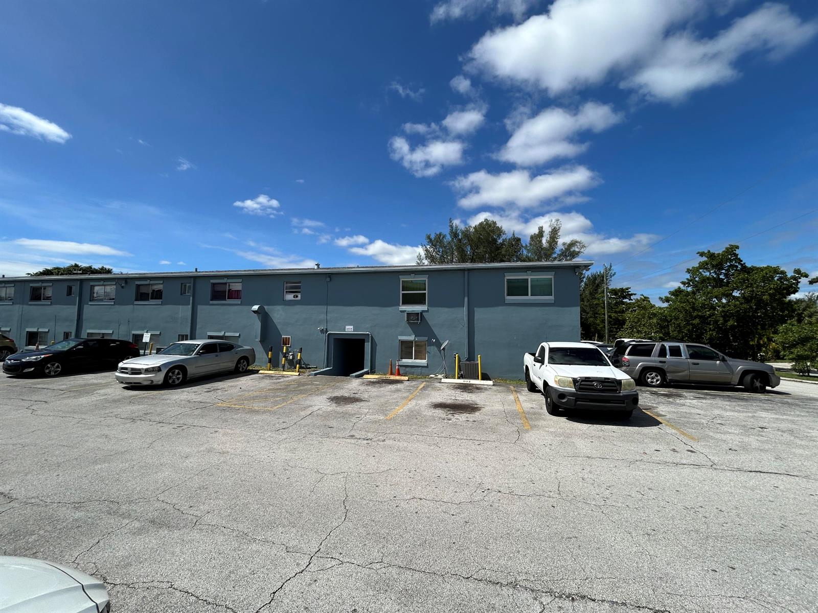 A two-story blue apartment building with a parking lot in front under a blue sky — 1829 N A Street # 65, FL 33460, FL