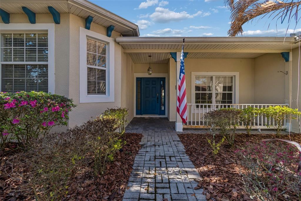A paved walkway leads to the front entrance of a house with a blue door — 162 TALL PINES PASS, KISSIMMEE, FL