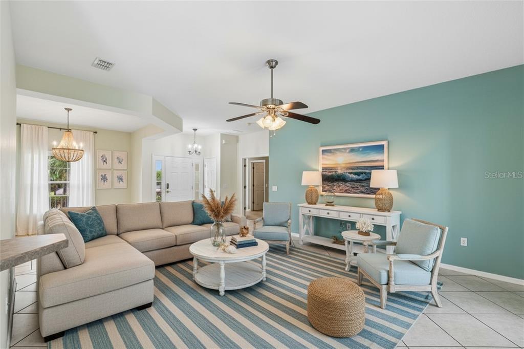A living room features a sectional sofa, striped rug, and a teal accent wall — 162 TALL PINES PASS, KISSIMMEE, FL