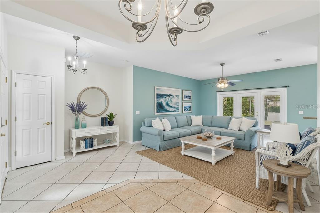 A living room features a blue sectional sofa, a coffee table, and a chandelier — 162 TALL PINES PASS, KISSIMMEE, FL