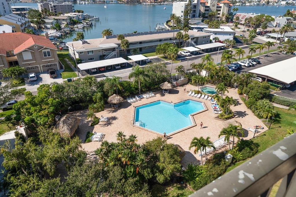 An aerial view shows a swimming pool surrounded by palm trees, lounge chairs, and buildings — 400 ISLAND WAY UNIT 901, CLEARWATER BEACH, FL