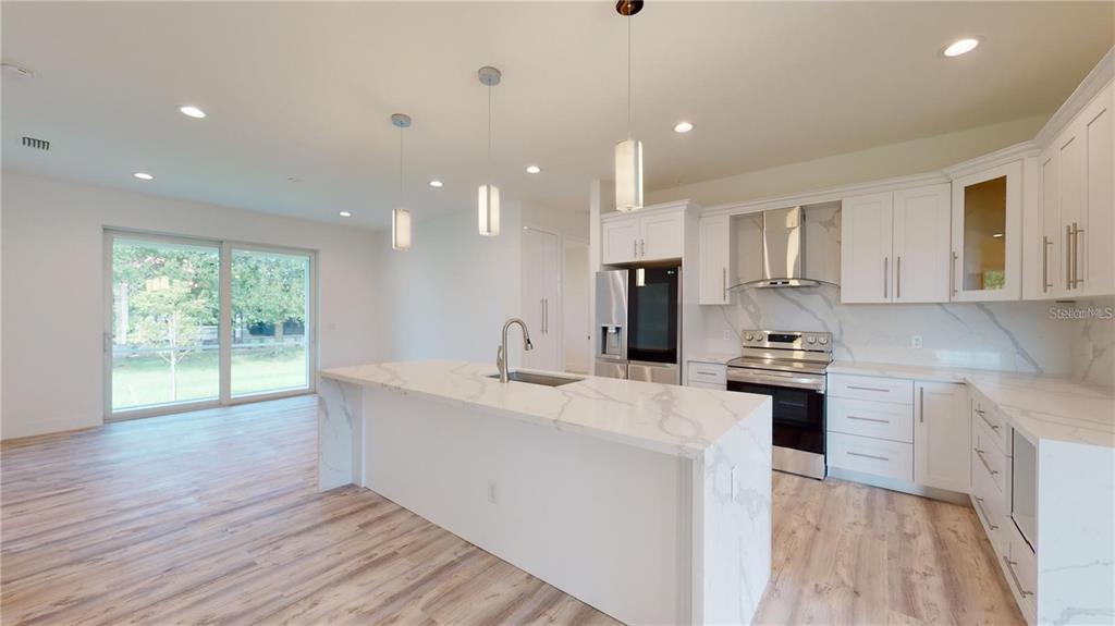 A modern kitchen features white cabinets, a marble-topped island, and stainless steel appliances — 17007 GINGER LANE, PUNTA GORDA, FL