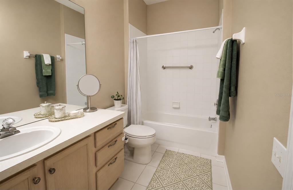 A bathroom features a vanity with a mirror, a toilet, and a shower-tub combination — 13560 TURTLE MARSH LOOP UNIT 338, ORLANDO, FL