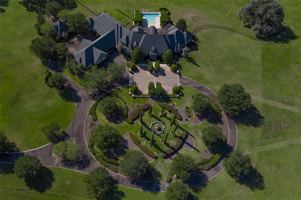 An aerial view shows a large house with a pool, circular driveway, and formal gardens — 9095 NW 200TH STREET ROAD, MICANOPY, FL