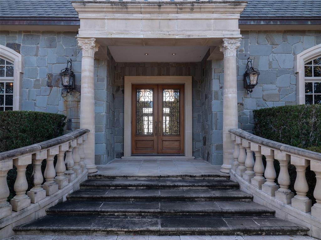 A stone house entrance features a double wooden door, columns, and a balustraded staircase — 9095 NW 200TH STREET ROAD, MICANOPY, FL