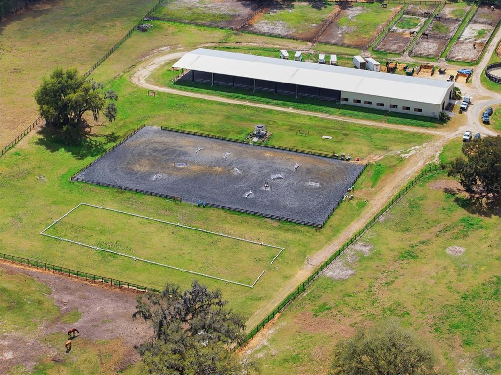 An aerial view shows a horse farm with a large barn, riding arena, and paddocks — 6025 NW 115TH AVENUE, OCALA, FL