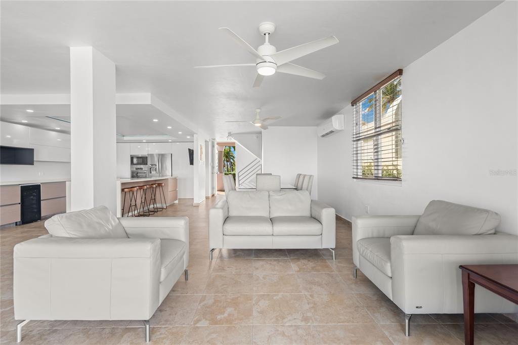 A bright living room features white leather furniture, tile flooring, and an open kitchen — J1 CALLE COSTA DORADA, DORADO, PR