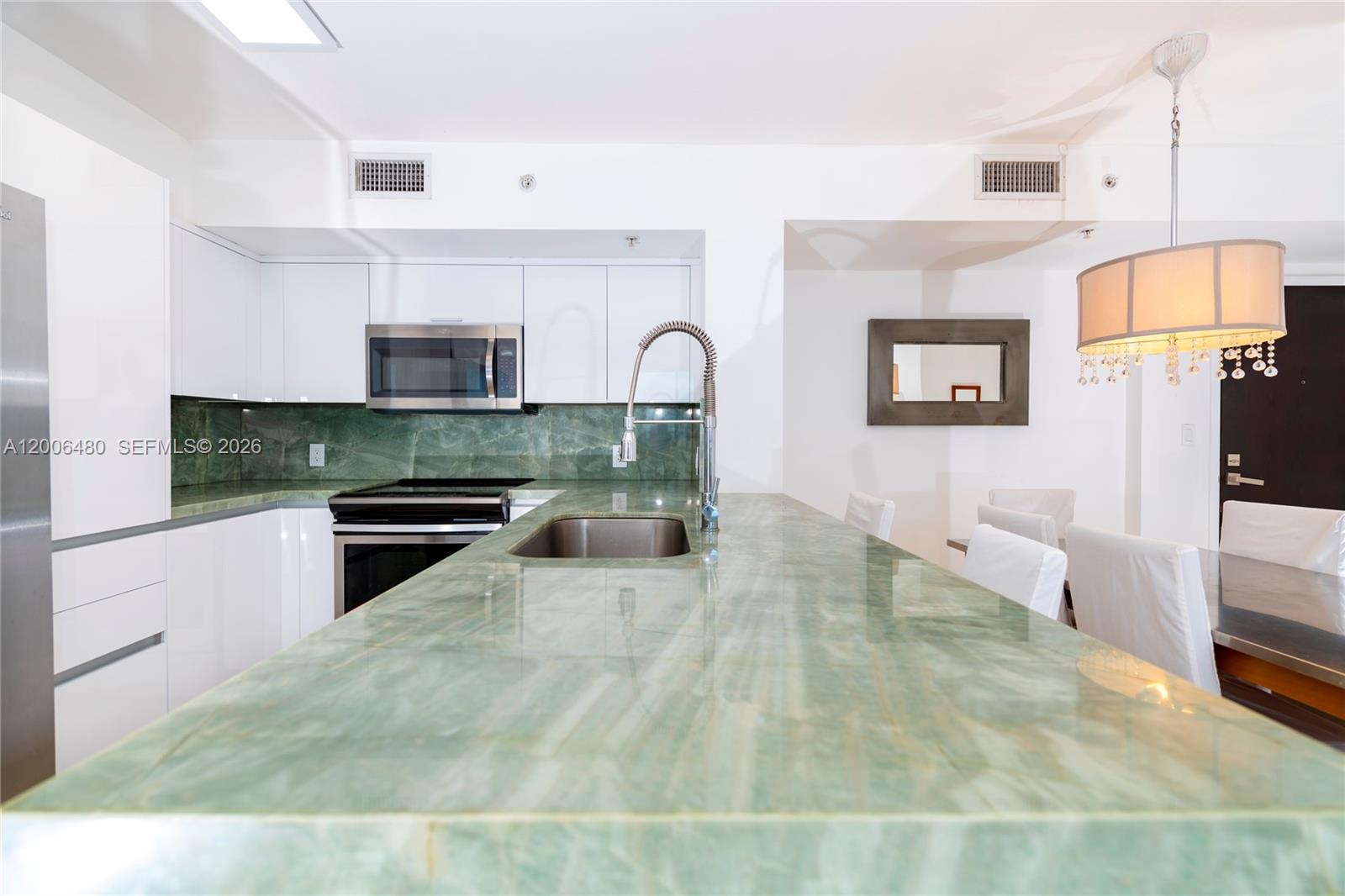 A modern living room features a white sectional sofa, a television console, and an open kitchen — 90 Alton Rd # 2304, Miami Beach FL 33139, MIAMI BEACH, FL