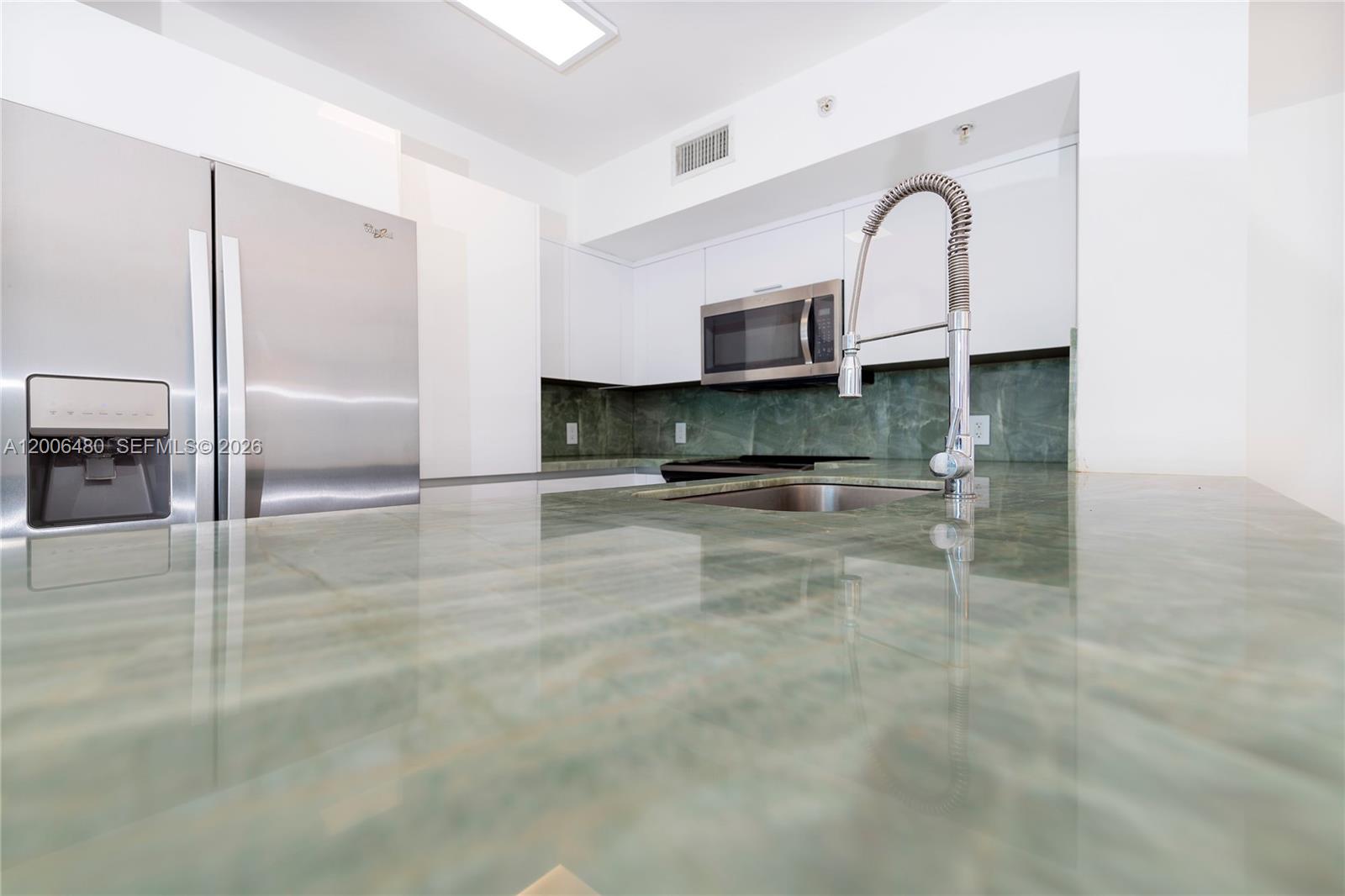 A modern living room features a white sectional sofa, a geometric rug, and an open kitchen — 90 Alton Rd # 2304, Miami Beach FL 33139, MIAMI BEACH, FL