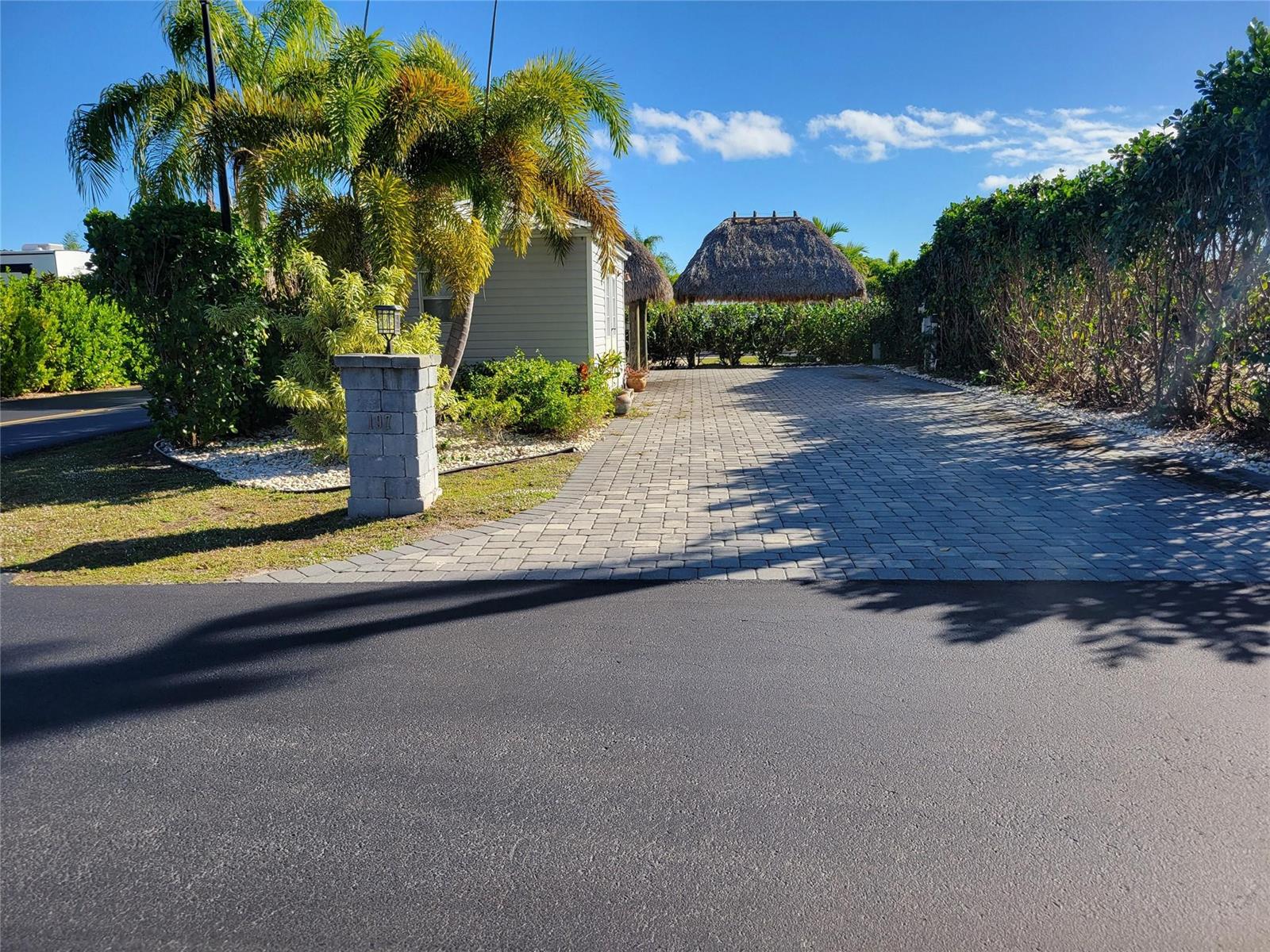 A paved driveway leads to a small house with a thatched-roof tiki hut in back — 3528 SW 7th Manor, Okeechobee FL 34974, OKEECHOBEE, FL