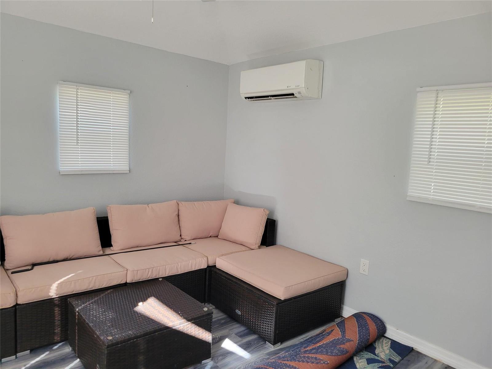 A room with light gray walls, a sectional sofa, and a wall-mounted air conditioning unit — 3528 SW 7th Manor, Okeechobee FL 34974, OKEECHOBEE, FL